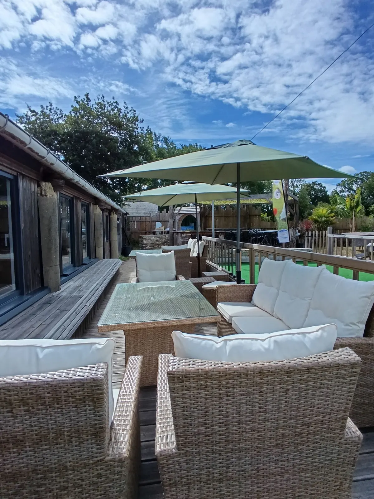 Salon de jardin en rotin et parasols sur la terrasse du bar